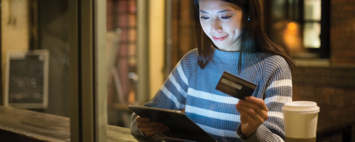photo of woman looking at tablet with credit card in hand