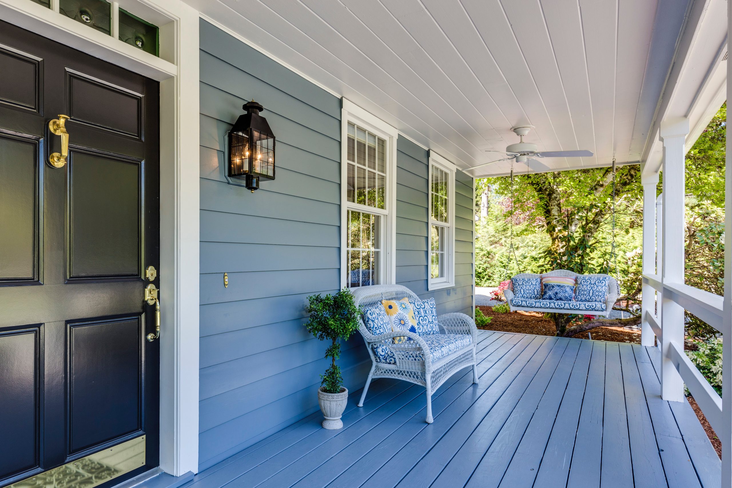 blue front porch of a house with a porch swing